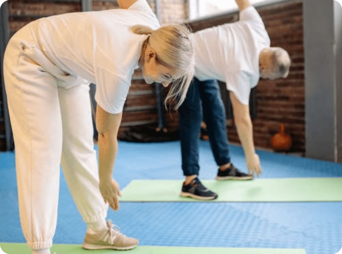 Two older adults stretching in an exercise class