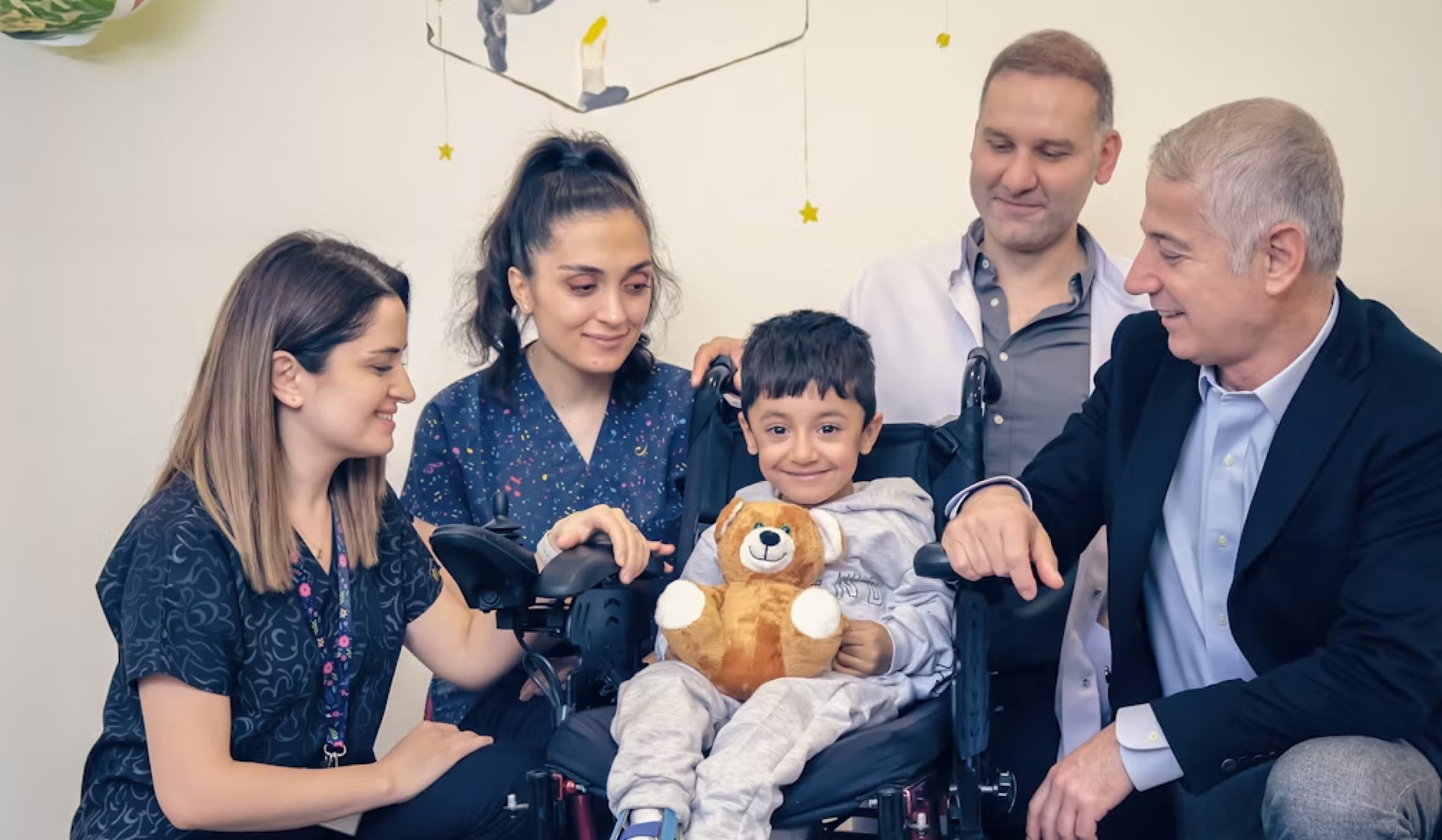 Smiling child in a wheelchair with family members