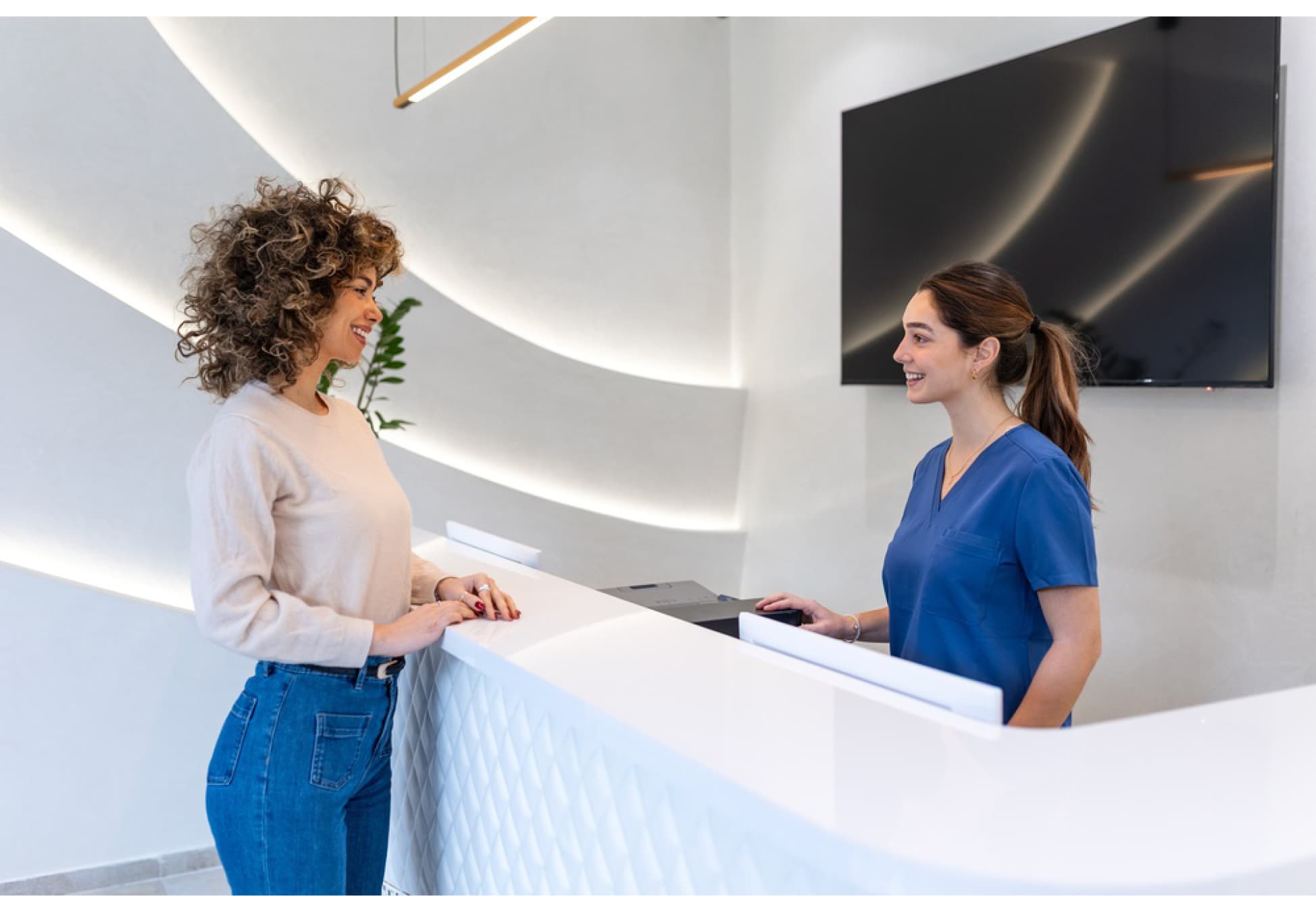 Smiling patient talking with a podiatry receptionist at the clinic front desk